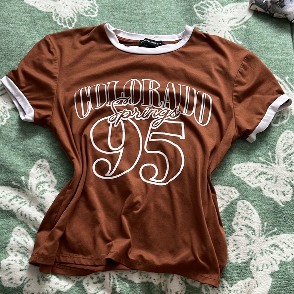 A lettered brown shirt with white hems